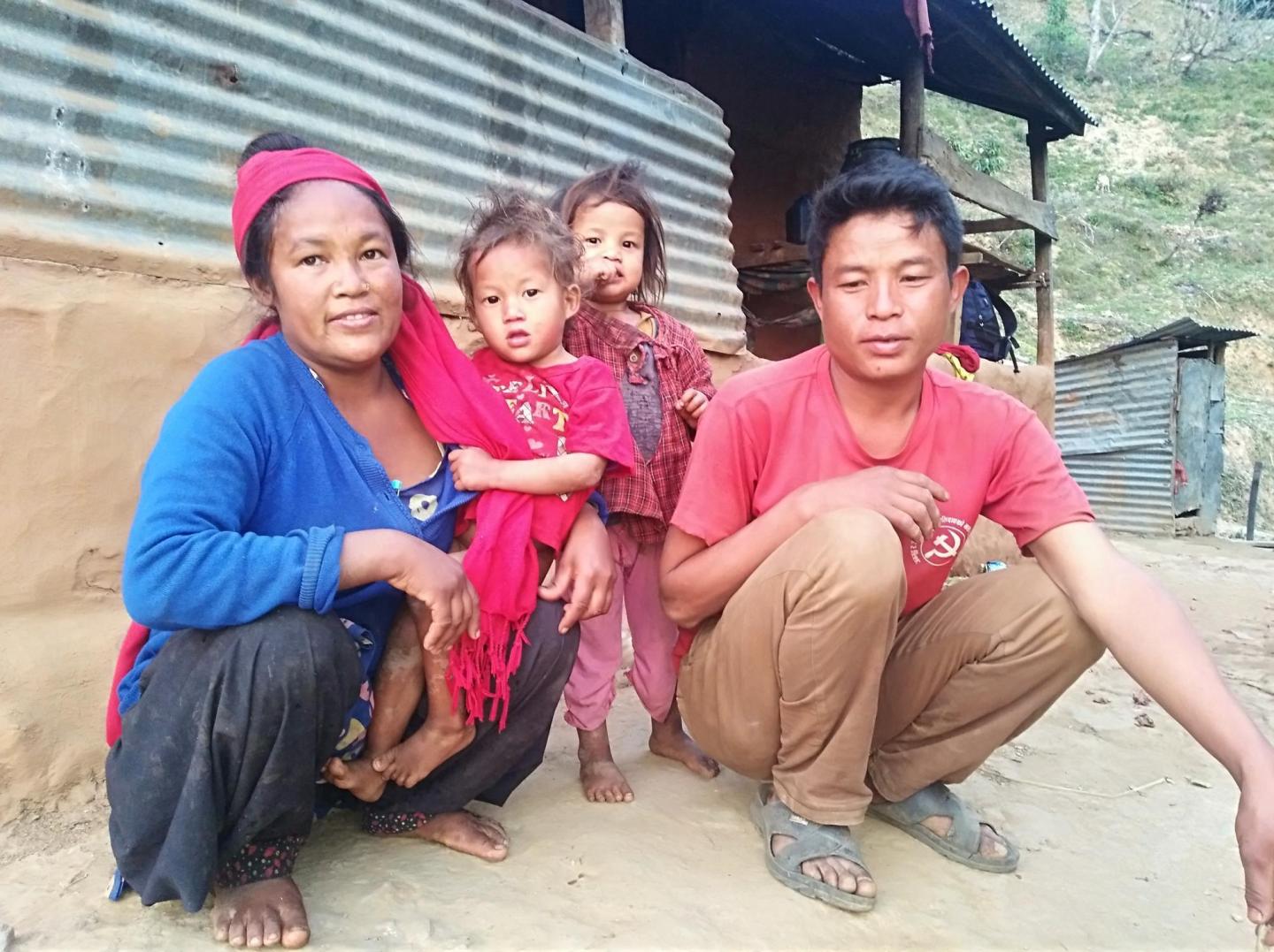 A Nepali family of four. The parents are squatting while the children stand in between them.