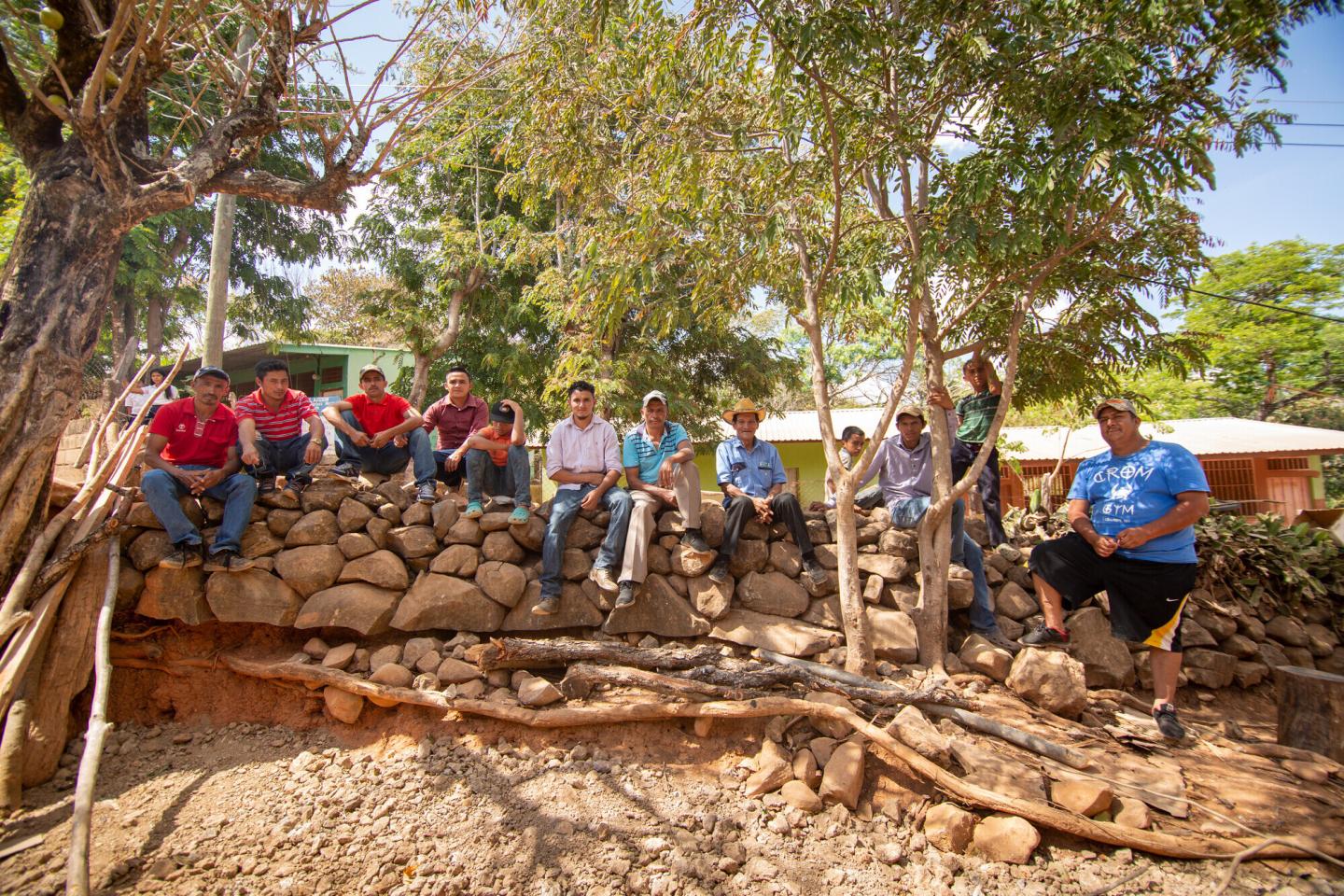 A group of Honduran men and boys sit on a stone wall