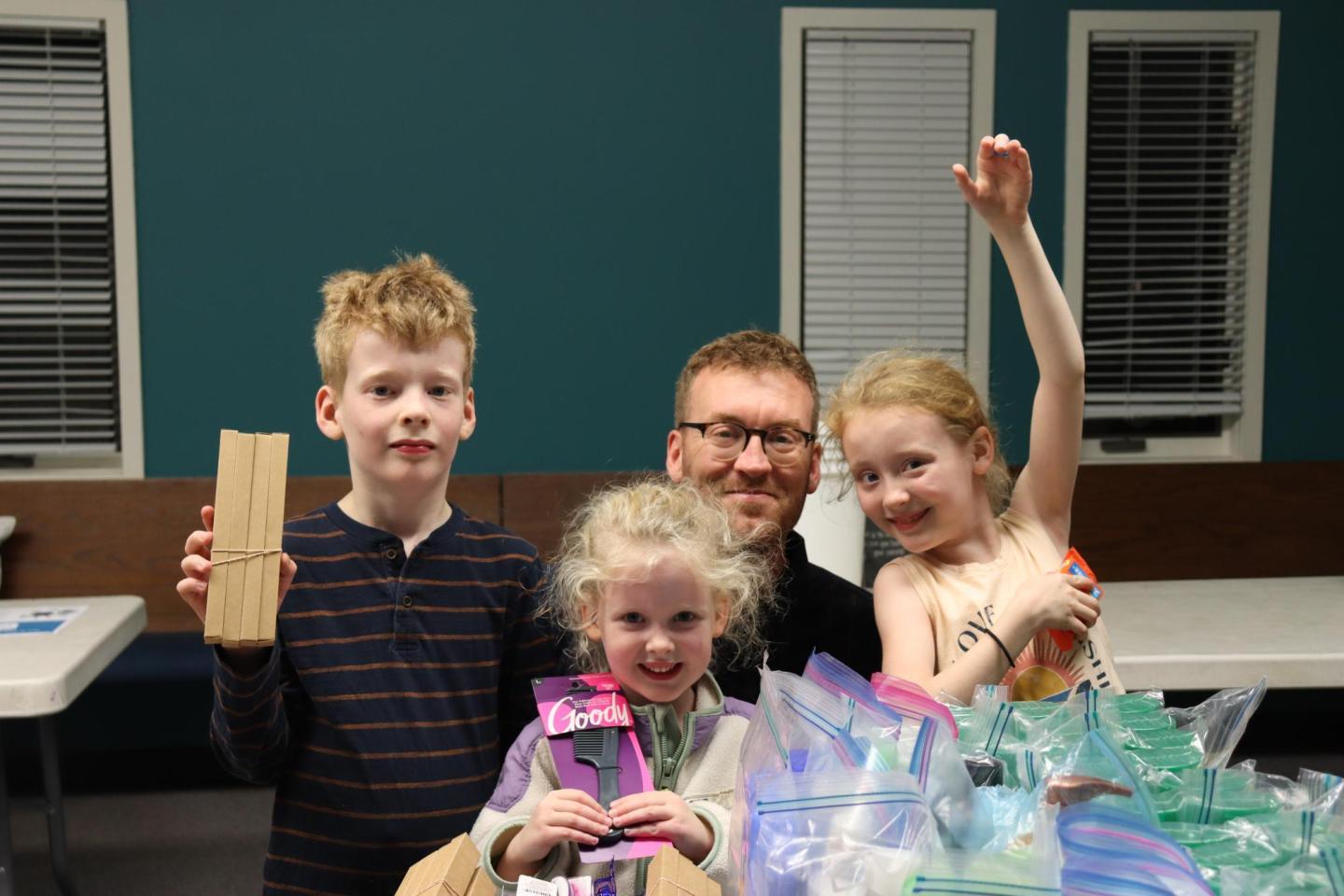 A father and his three children pose with hygiene items 