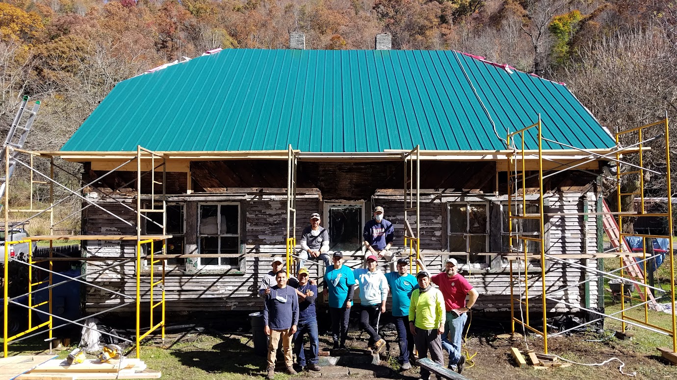 group of people standing in front of a house under construction