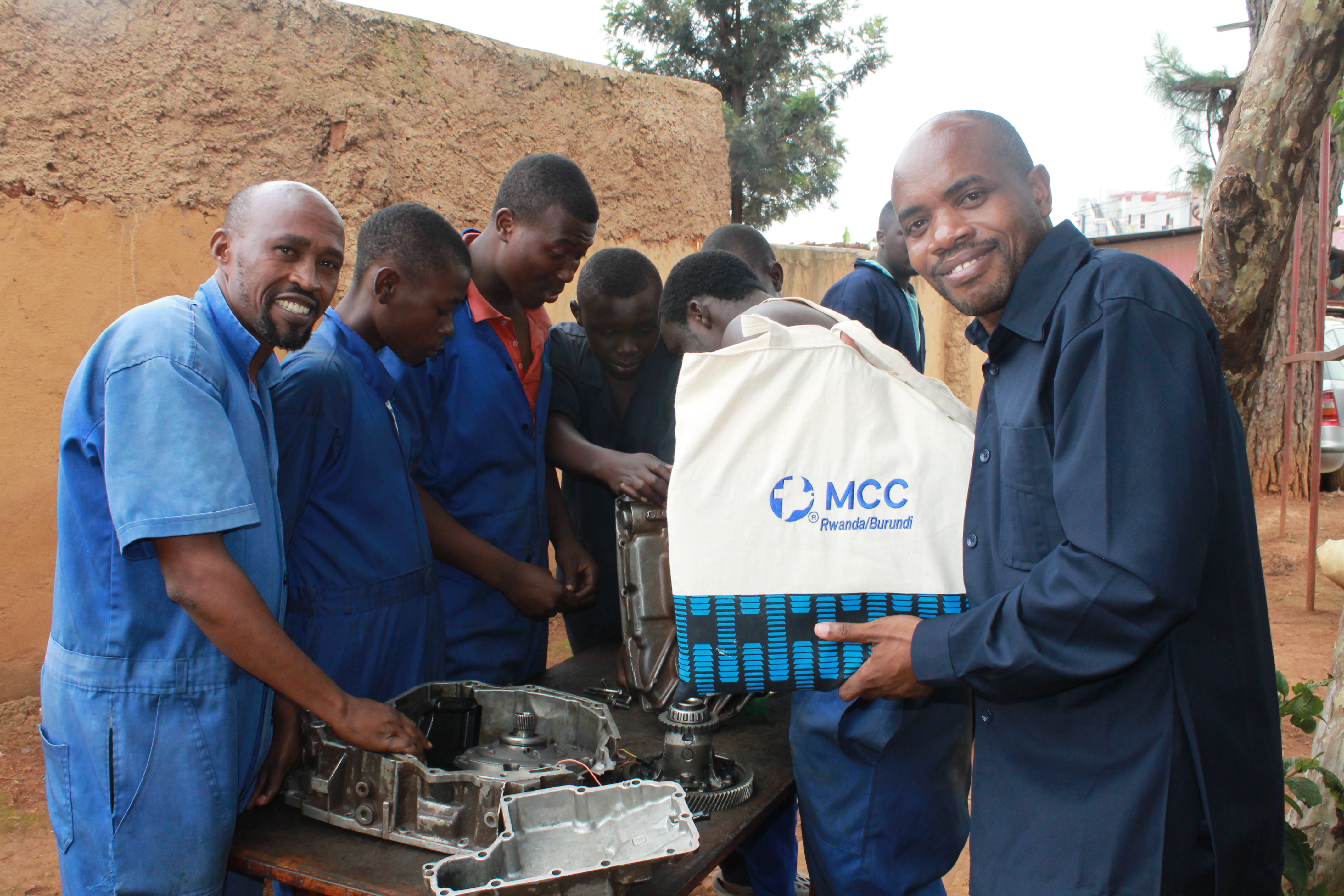 a group of participants in a vocational training session surround an engine