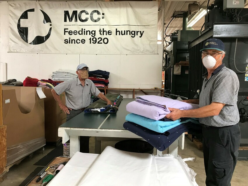 Volunteers Dennis Diller (Leola, Pennsylvania) and Melvin Weaver (Reinholds, Pennsylvania) fold comforters at the MCC East Coast Material Resources Center in Ephrata, Pennsylvania, in August of 2020.