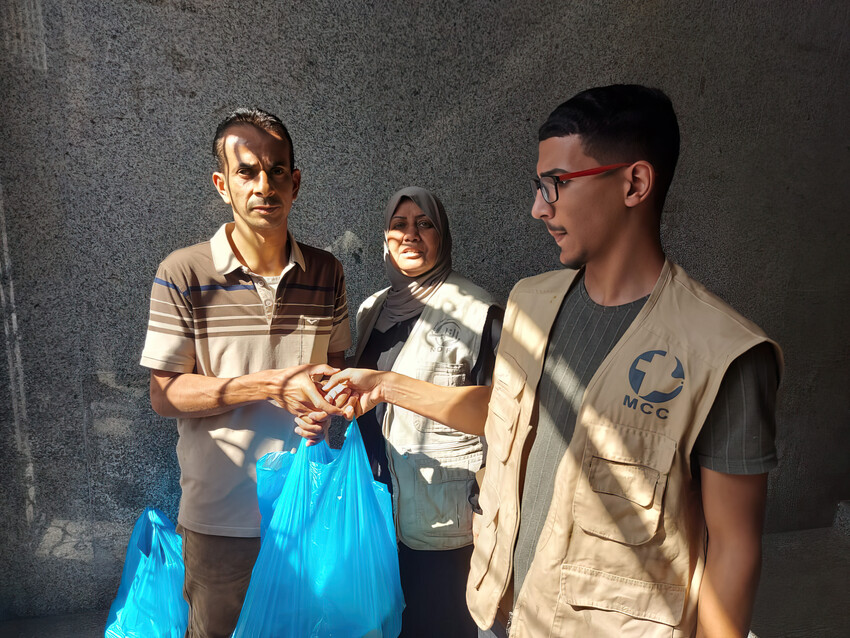 On October 17, 2023, Firas Hamlawi, right, a volunteer and Rifqah Hamlawi, center, a staff member, with  Al-Najd Developmental Forum, helped distribute food packages to 35 families and bedding to 10 f