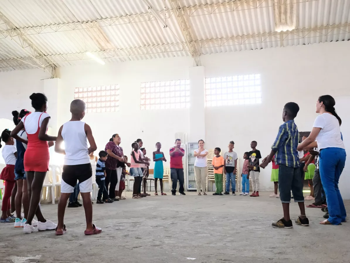 A group of adults and kids stand in a semi circle 