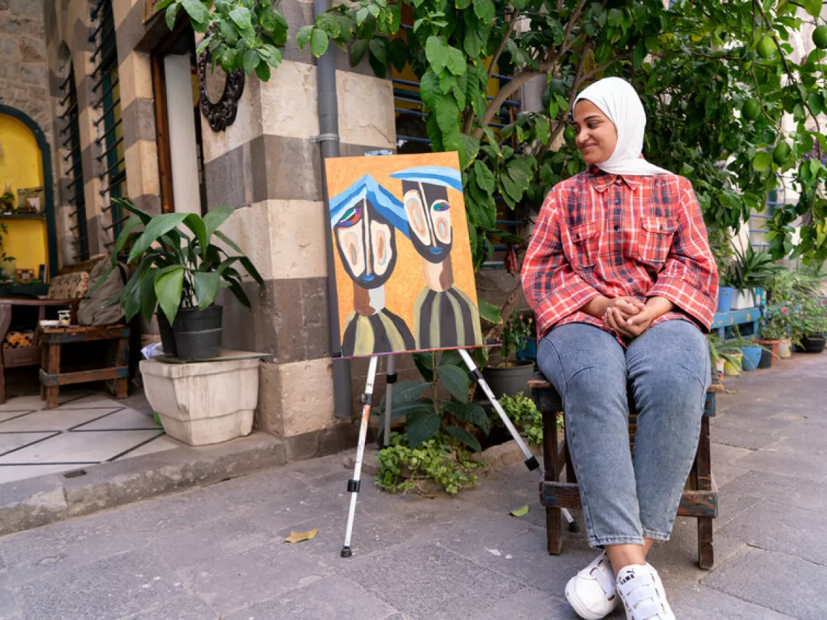 Aya Abdullah Fadi, 21,  with her painting, ”Two Prisoners” that appeared in the Beyond Colors art exhibition in Homs, Syria.