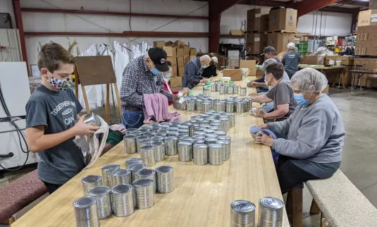 Group of volunteers putting labels on cans.