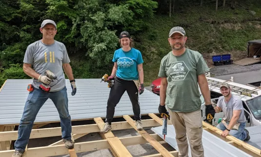 three people working on roof of house