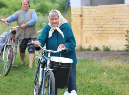 A woman holding a bike and relief bucket