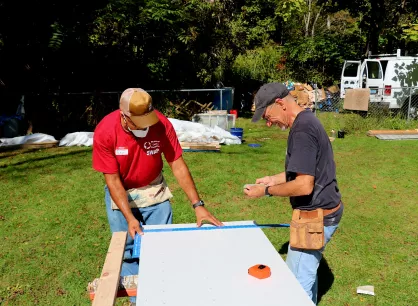 two men work together to measure and cut drywall