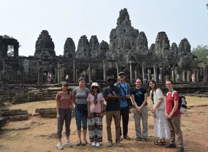 Eight young people standing in front of an ancient building