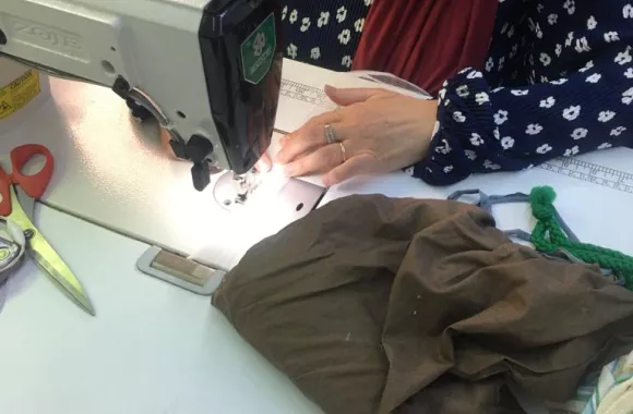 A woman sits and works at a sewing machine.