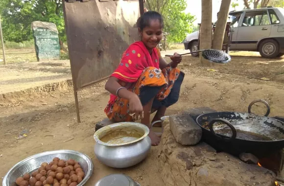 Amrita Topno is frying a sweet snack called “gulgula” made out of wheat flour, over a wood fire, to sell in the local haat (open air market) in Potab village. Topno, a member of the Kuni self-help gro