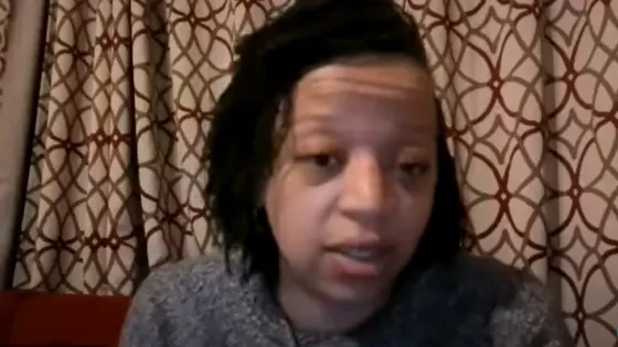 A woman with short dreads speaks into the camera during a video call