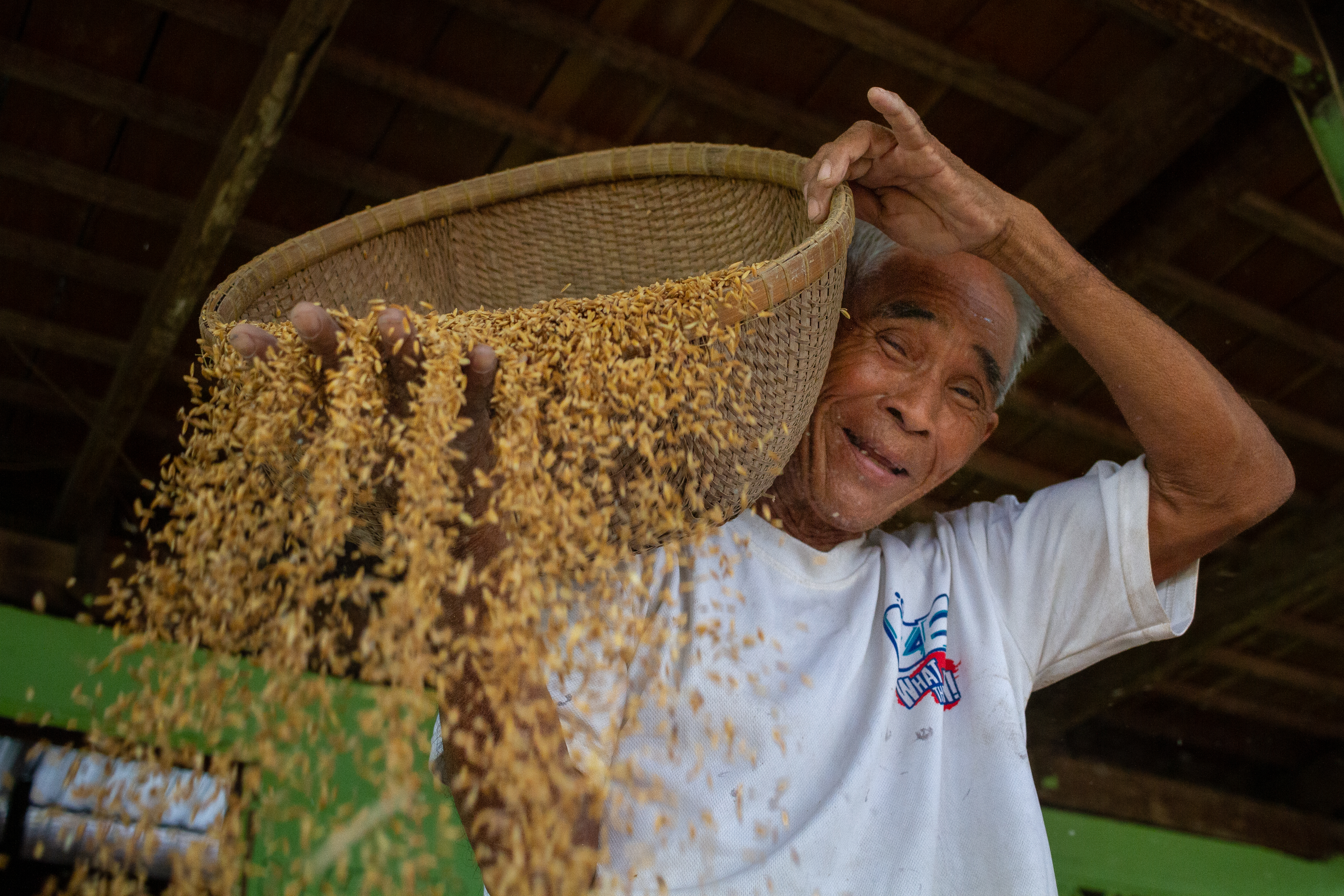 Phean Sorn winnows rice in the shade of his family home in Mesang, Cambodia. Winnowing is done to remove empty rice husks and other impurities from the unmilled rice. This is seed rice to plant the next crop as the rainy season approaches and the largest rice crop of the year begins.