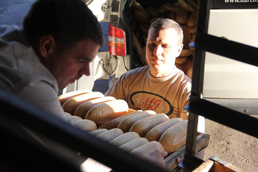 A man gives another man a tray of bread loaves in Ukraine