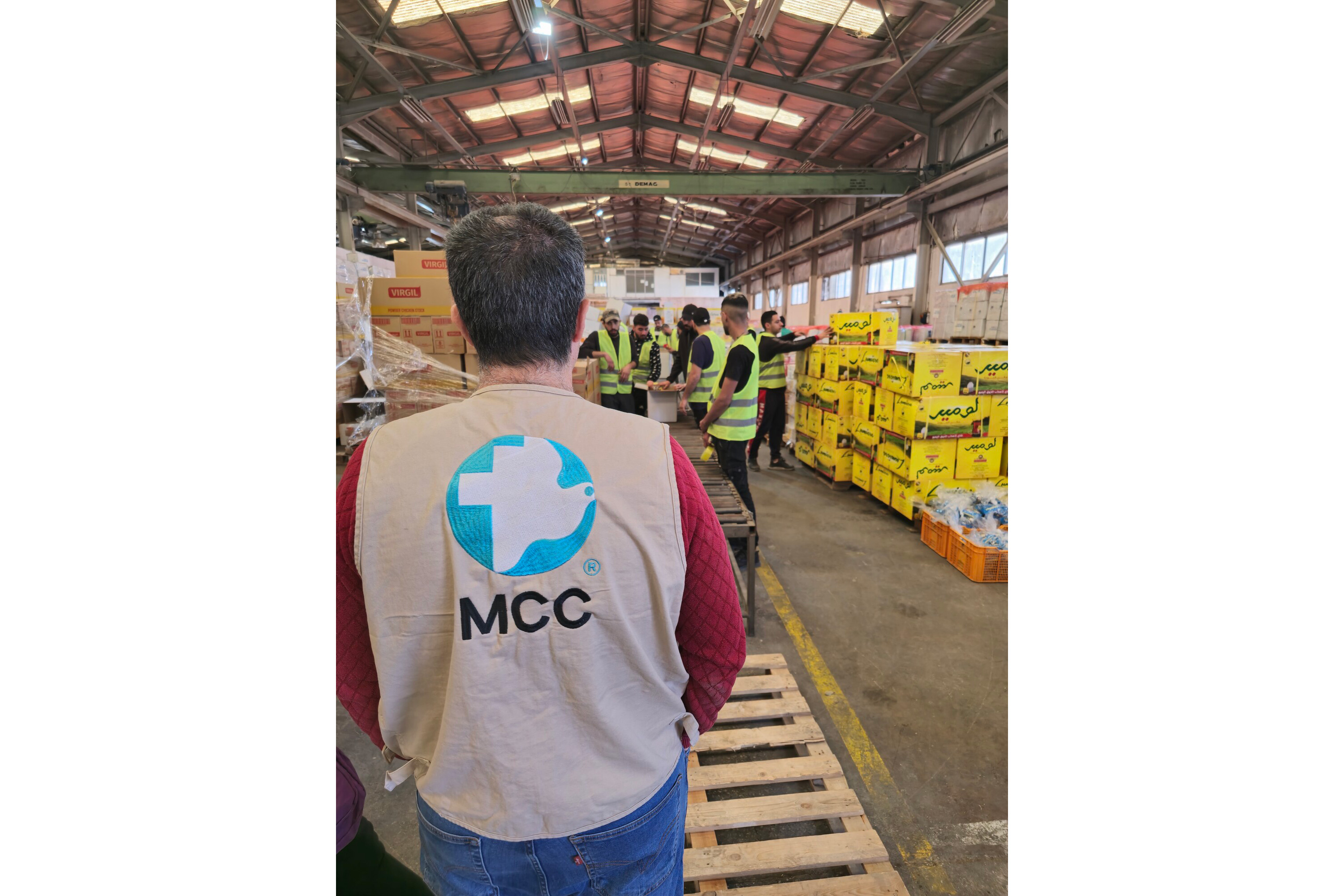 A person wearing a a vest with an MCC logo in a warehouse