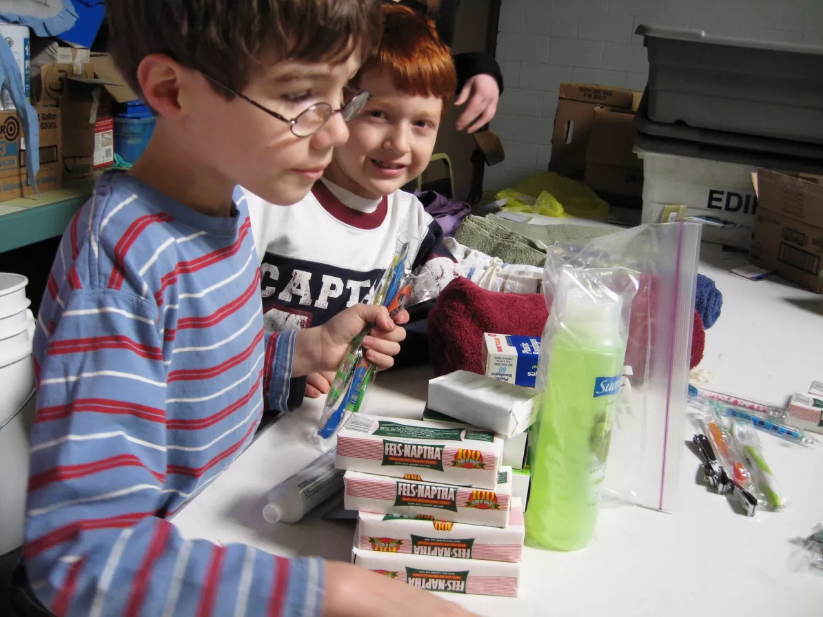 Two kids work with hygiene items on a table