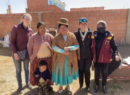 Five adults and one child stand together and smile at the camera