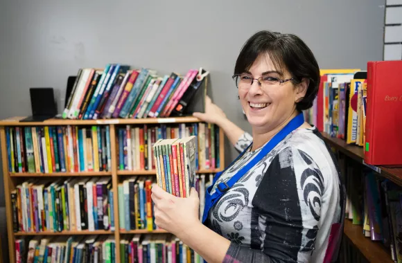 A volunteer stocking books at an MCC thrift shop