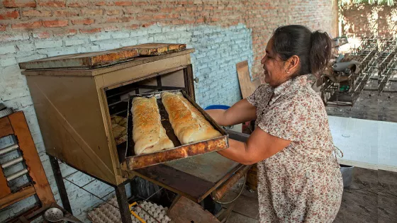 A  Bolivan woman pulls baked goods out of an oven